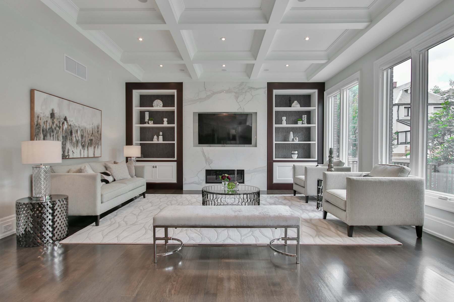 Bright living room with a marble fireplace, built-in shelves, and tall windows
