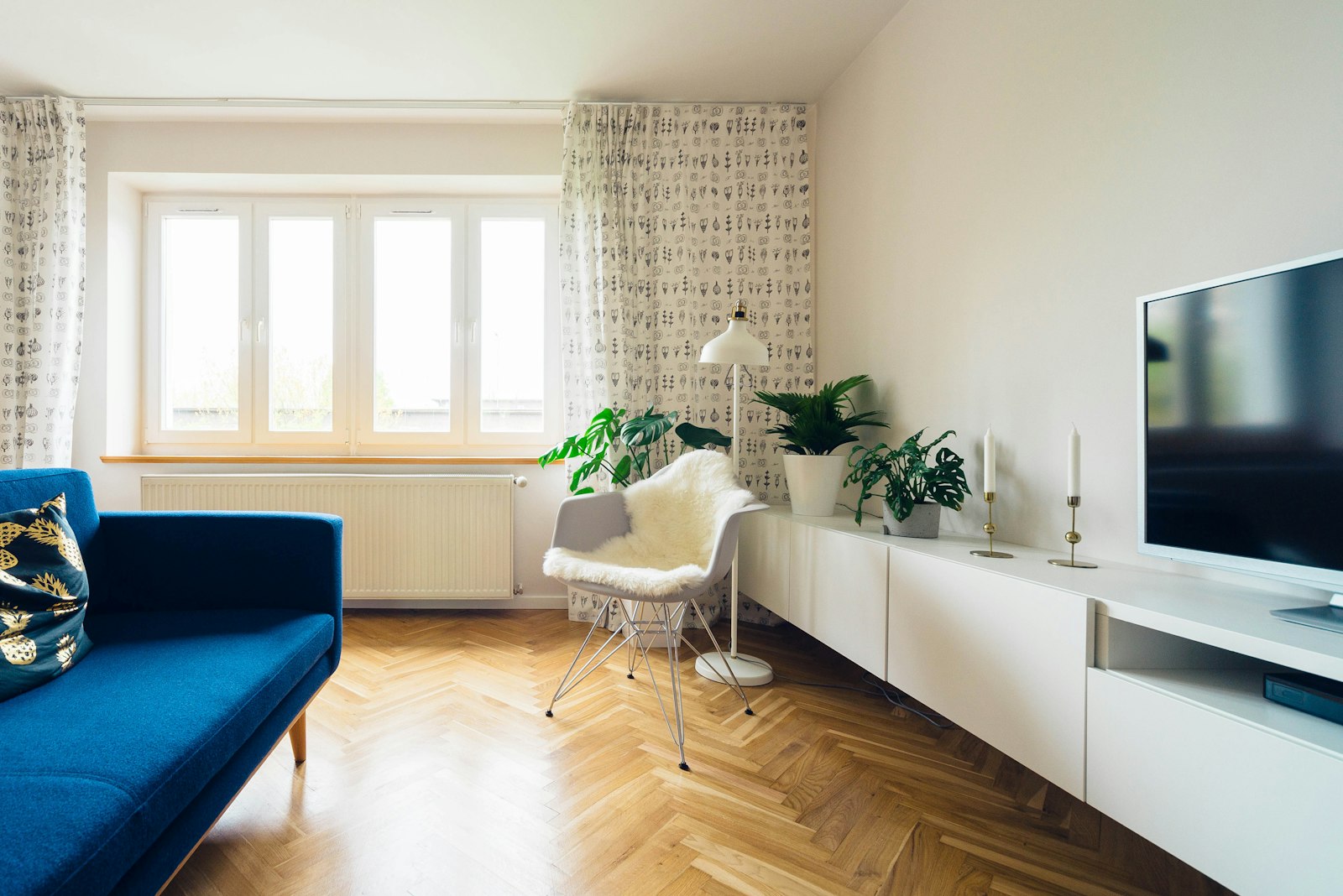 Living room with a blue sofa, herringbone wood floor, and a long window